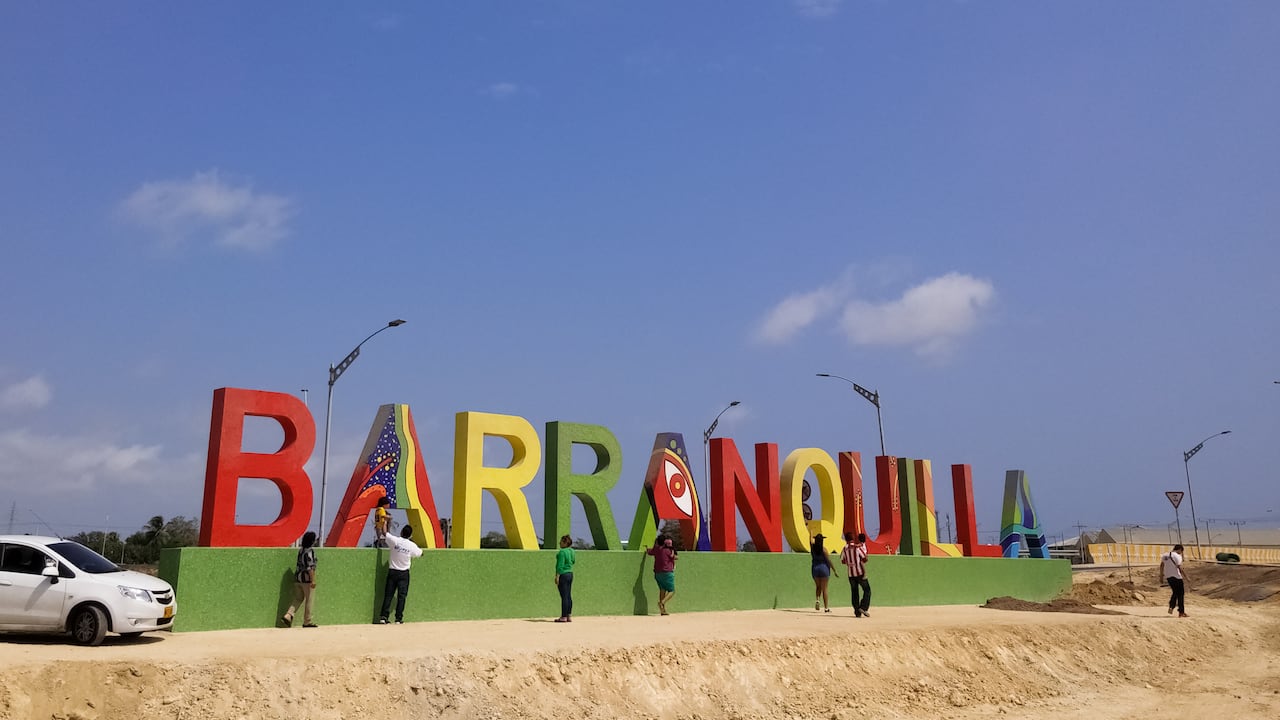 Turistas cerca de un gran cartel con letras.