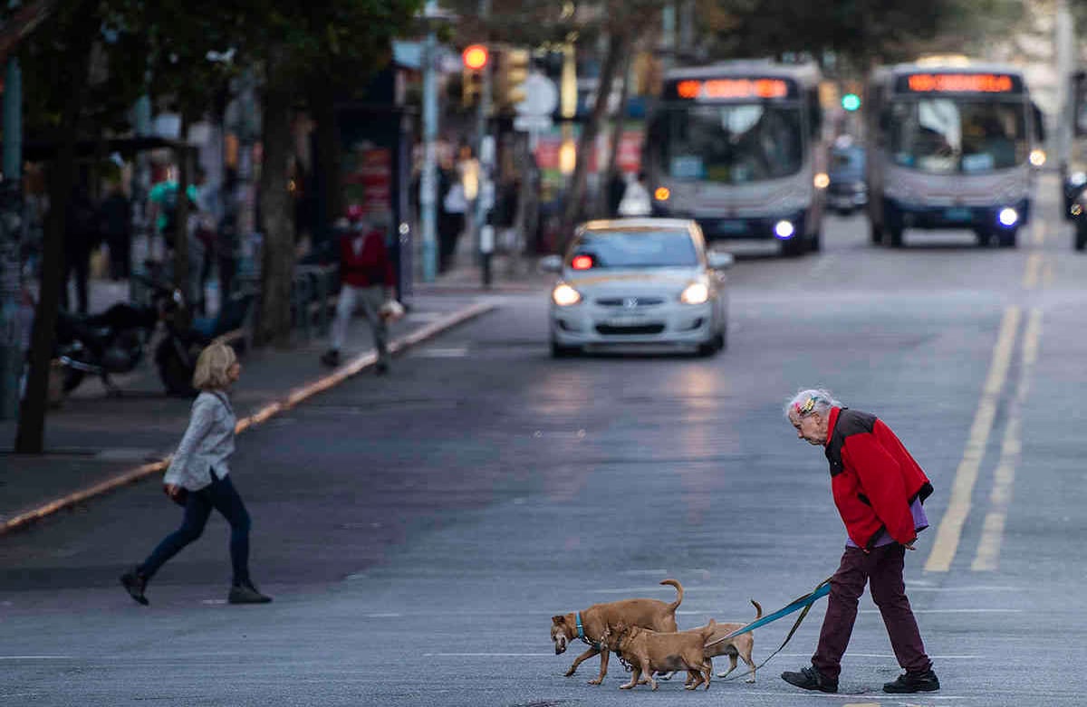 Una mujer mayor y sus mascotas cruzan una calle en Montevideo, Uruguay. (Foto AP / Matilde Campodonico)