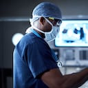 Disparo de un cirujano mirando un monitor en una sala de operaciones.