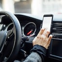 Close up of a female hand using phone to search the location while driving a car. Woman using gps navigation on her mobile phone while driving a car.