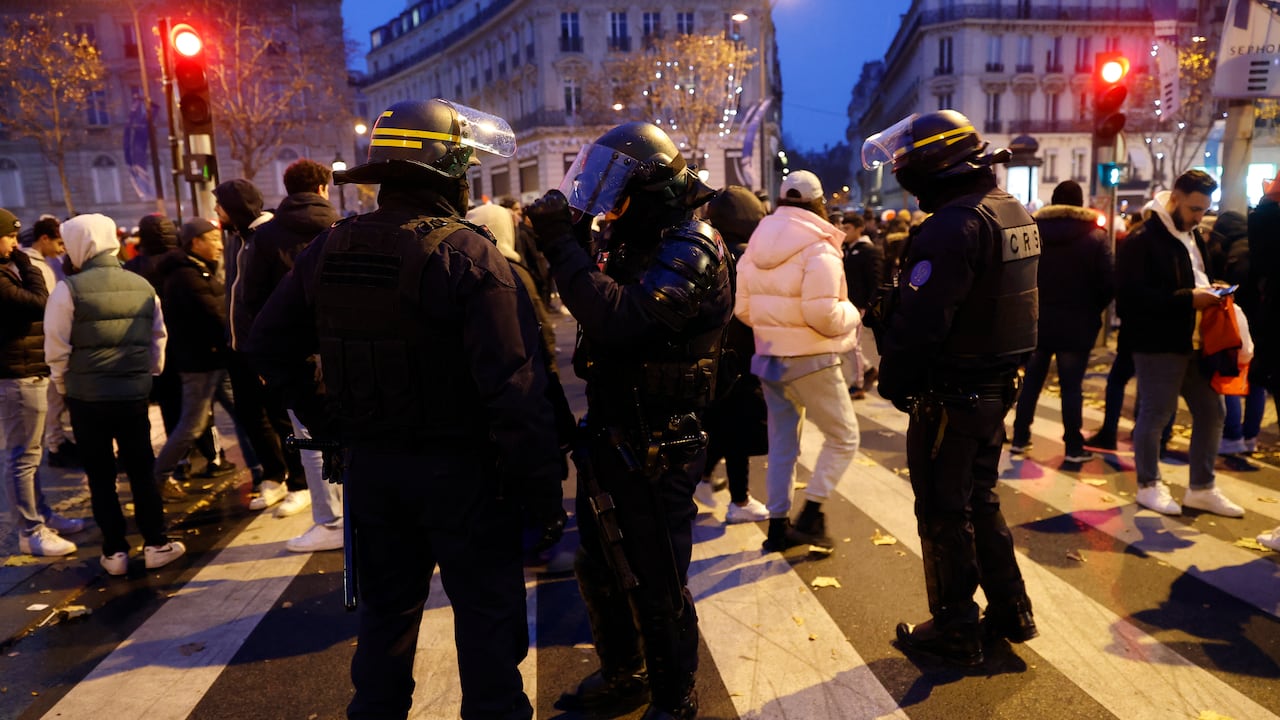 Policías antidisturbios pasan por delante de los aficionados al fútbol de Francia que se reunieron para ver el partido de fútbol final de la Copa del Mundo Qatar 2022 entre Argentina y Francia cerca de la Avenue des Champs-Elysees, en París el 18 de diciembre de 2022. (Foto de ROMAIN PERROCHEAU / AFP)