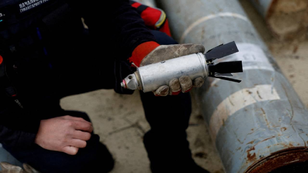Militar ucraniano sostiene una bomba de racimo desactivada.