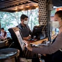 Retrato de una mujer que trabaja en el cajero de un restaurante con un tapabocas conceptos de ocupación del servicio de alimentos.