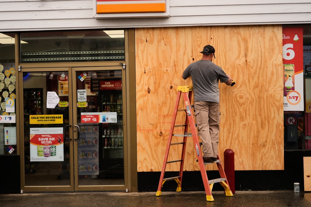 Jason Coffey coloca tablones en una tienda en una gasolinera mientras el huracán Isaías se acerca a Pensacola Beach, Florida, el viernes 9 de octubre de 2026. (AP Foto/Gerald Herbert)