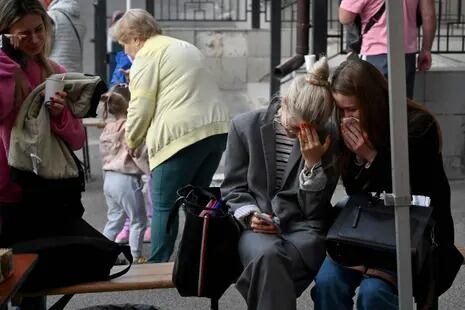 Los residentes reaccionan frente a un edificio residencial de varios pisos, parcialmente destruido después de los ataques nocturnos con drones en Kiev el 30 de mayo de 2023.