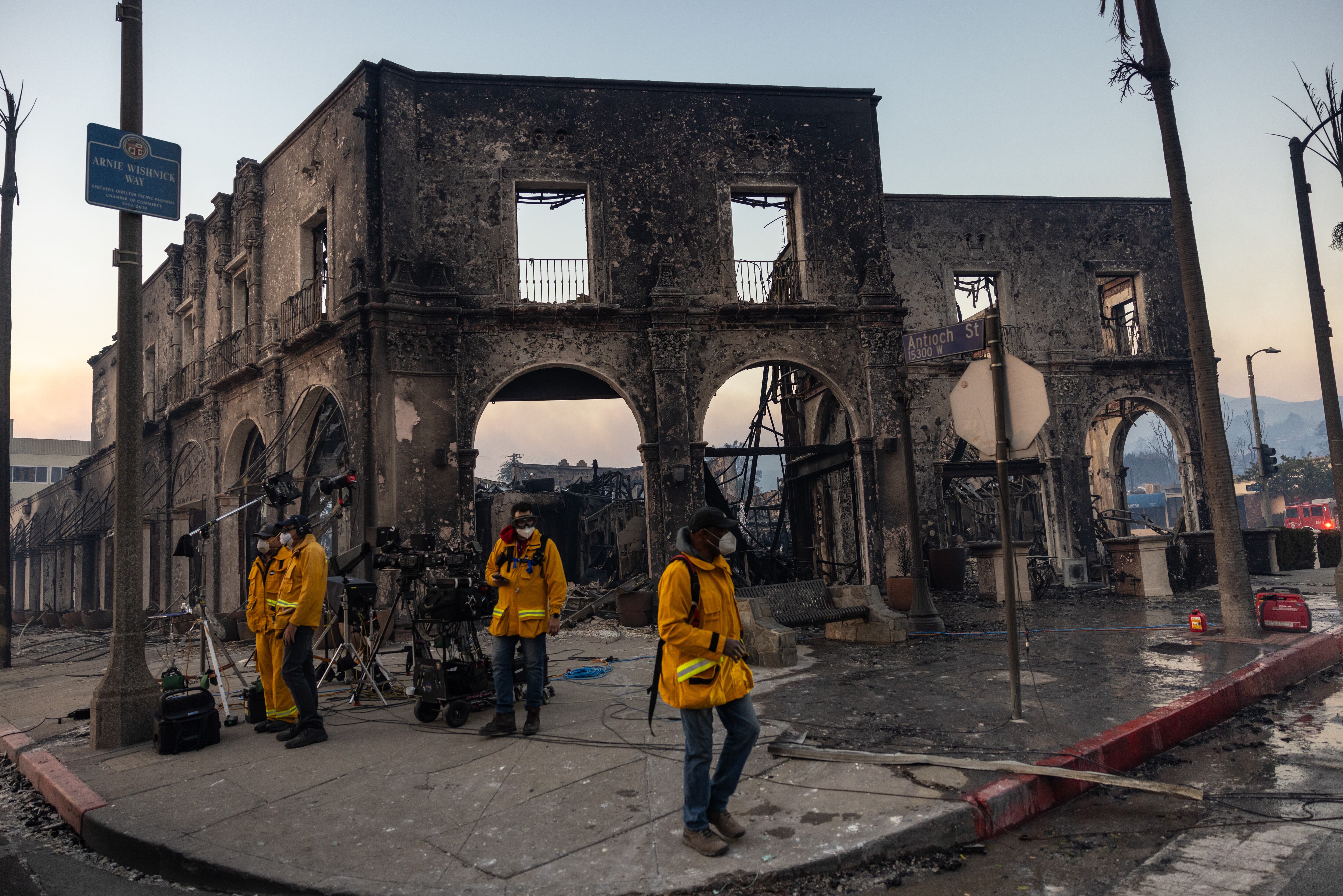 PACIFIC PALISADES, CALIFORNIA - JANUARY 08: Members of the media, in front of the building where the Starbucks coffee shop was located, destroyed in the Palisades Fire, on January 8, 2025 in the Pacific Palisades community. Multiple wildfires fueled by intense Santa Ana Winds are burning across Los Angeles County. Five people have been killed, over 25,000 acres have burned, and 30,000 people have been evacuated. (Photo by Jay L. Clendenin/Getty Images)