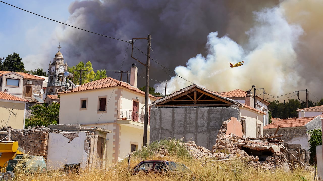 Un avión de bomberos arroja agua sobre un incendio forestal mientras el humo se eleva cerca de la aldea de Vrisa, en la isla oriental del Egeo de Lesbos, el domingo 24 de julio de 2022. Un incendio que se desató el sábado por la mañana en la isla griega de Lesbos llevó a las autoridades a pedir la evacuación del complejo turístico de Vatera, en el lado sur de la isla. (AP Foto/Panagiotis Balaskas)