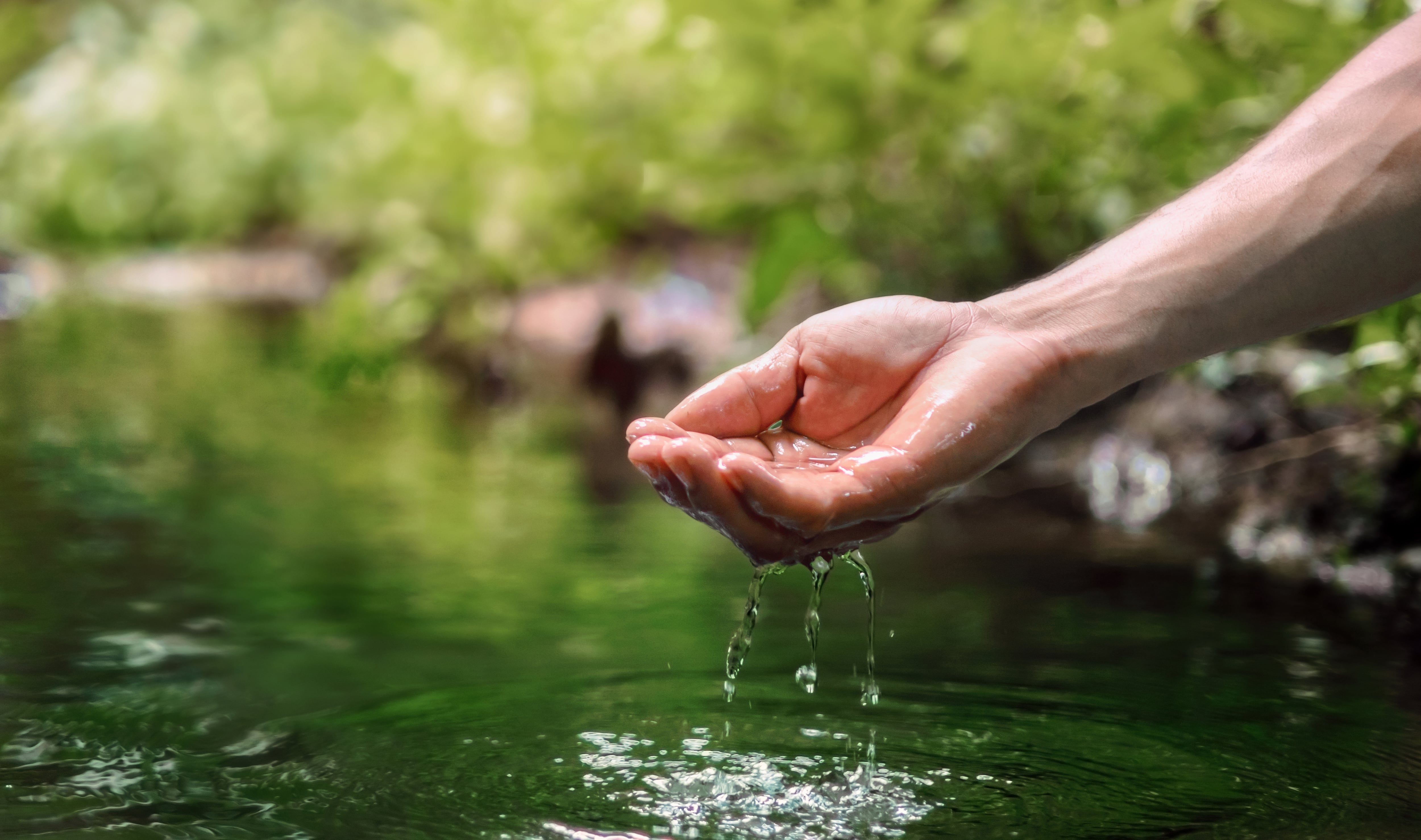 hand is holding a stream of water. Concept of calm and tranquility, as if the person is simply enjoying the moment of being in the water