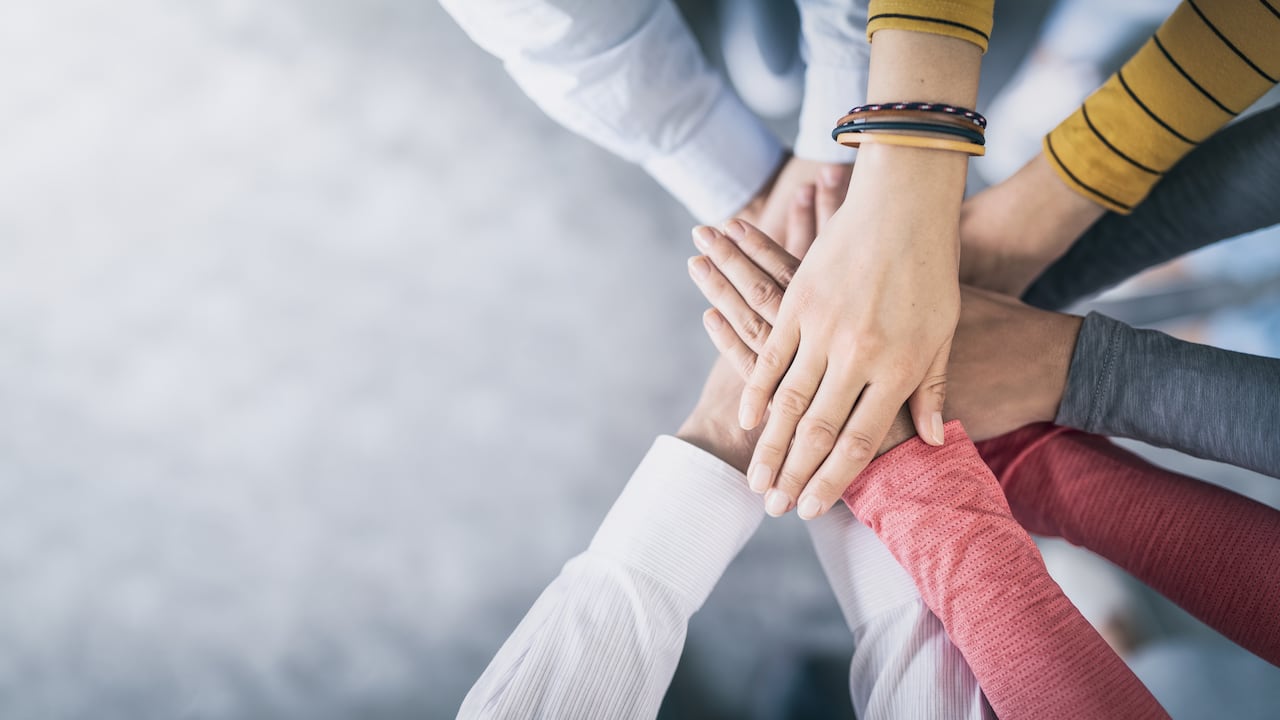 Cerrar vista superior de jóvenes empresarios juntando sus manos. Pila de manos. Concepto de unidad y trabajo en equipo.