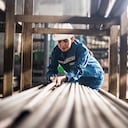 Mujer de una fábrica de acero en el trabajo moviendo postes de acero