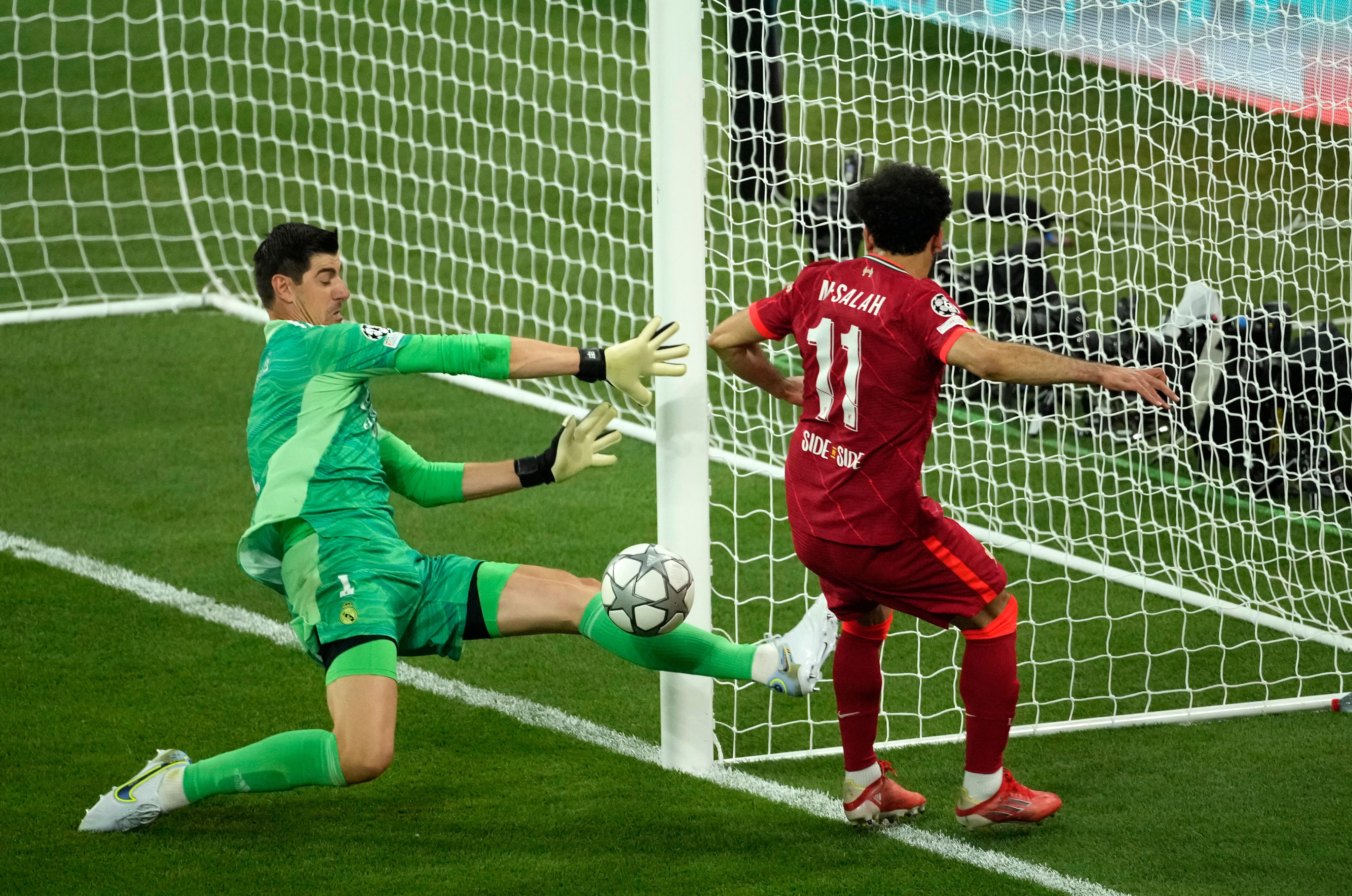Real Madrid's goalkeeper Thibaut Courtois, left, makes a save in front of Liverpool's Mohamed Salah during the Champions League final soccer match between Liverpool and Real Madrid at the Stade de France in Saint Denis near Paris, Saturday, May 28, 2022. (AP Photo/Christophe Ena)