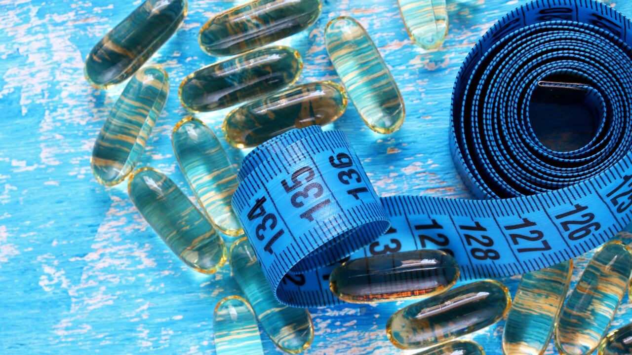 Pastillas y cinta métrica sobre fondo azul