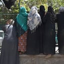 Internally displaced Afghan women, who fled from the northern province due to battle between Taliban and Afghan security forces, gather to receive free food being distributed by Shiite men at Shahr-e-Naw Park in Kabul on August 13, 2021. (Photo by WAKIL KOHSAR / AFP)
