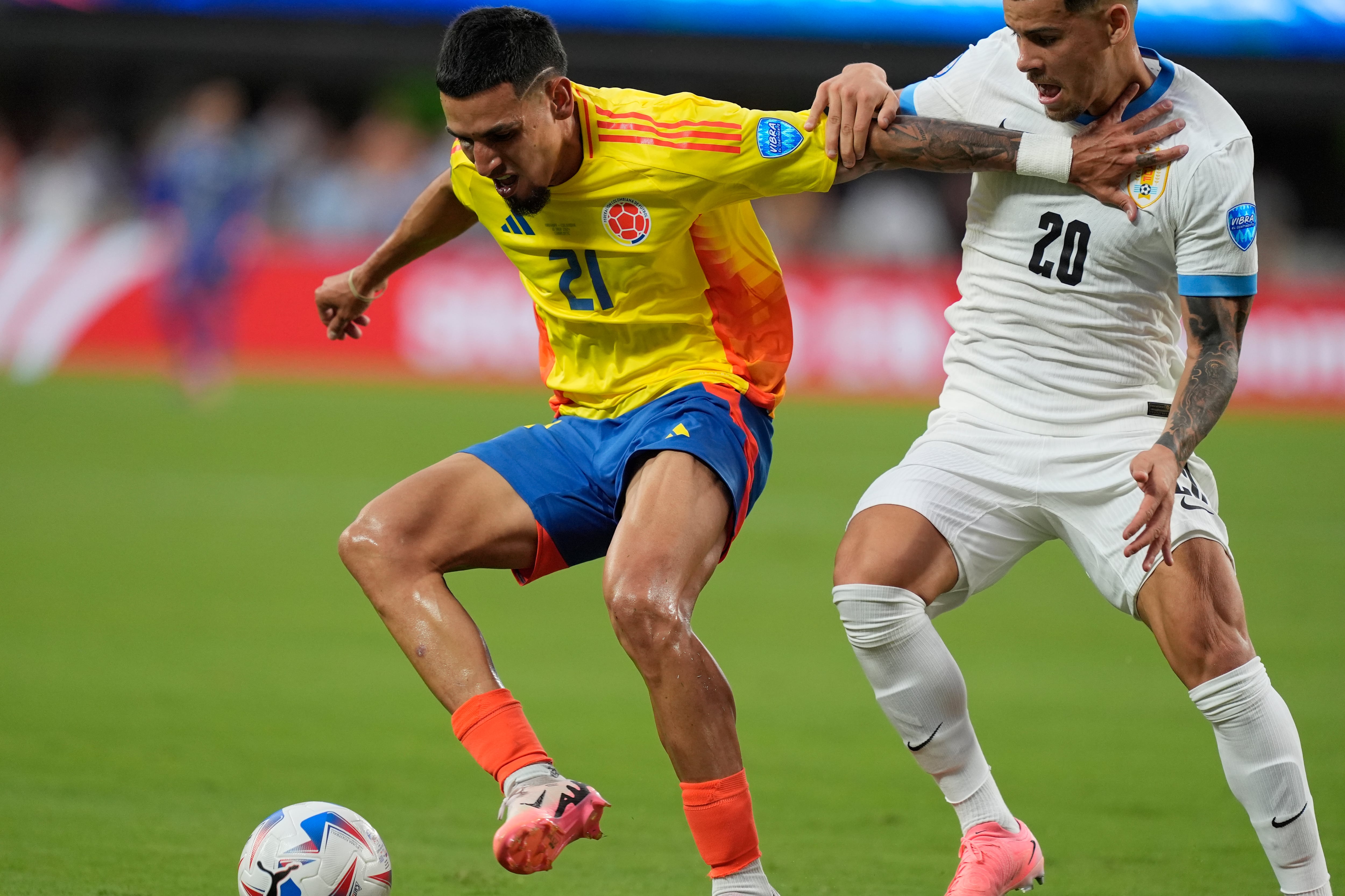 El colombiano Daniel Muñoz (21) y el uruguayo Maximiliano Araujo luchan por el balón durante un partido de fútbol semifinal de la Copa América en Charlotte, Carolina del Norte, el miércoles 10 de julio de 2024. (Foto AP/Julia Nikhinson)