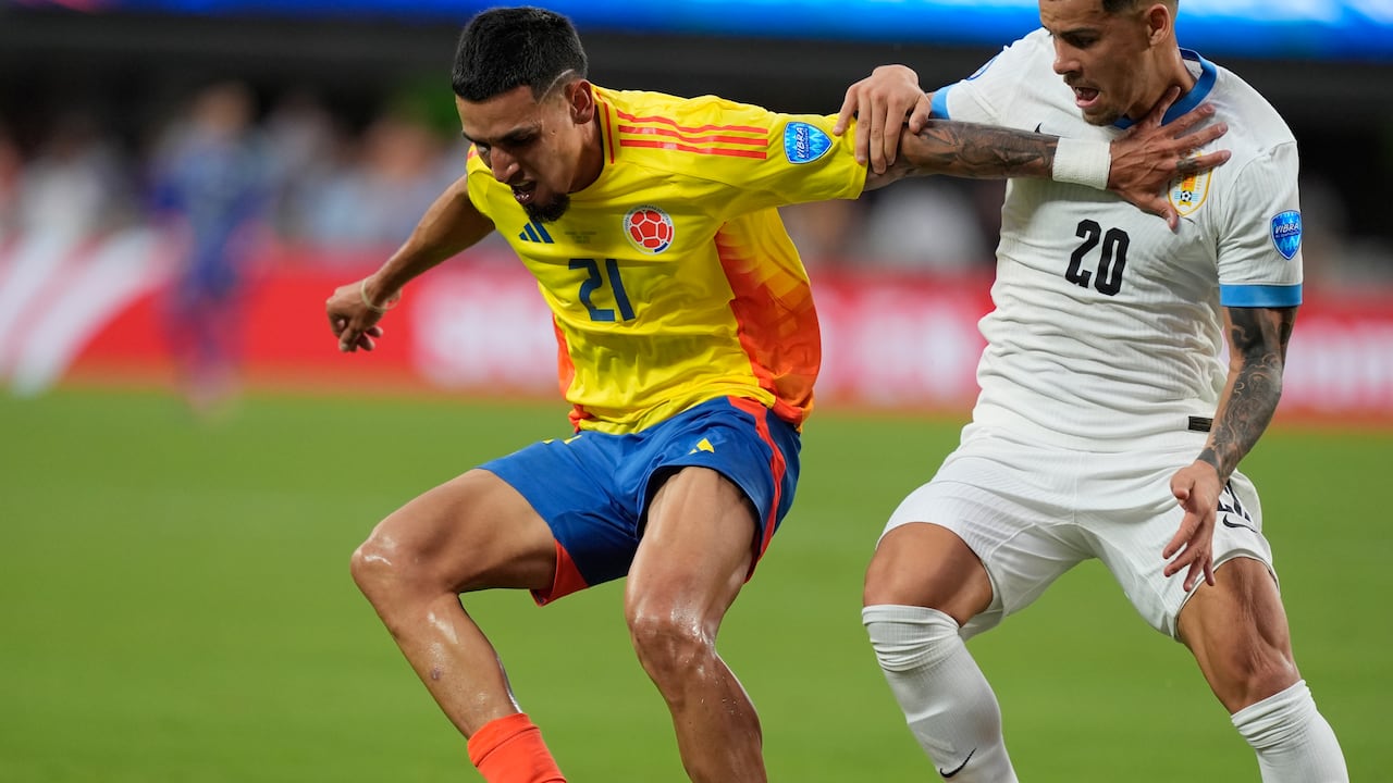 El colombiano Daniel Muñoz (21) y el uruguayo Maximiliano Araujo luchan por el balón durante un partido de fútbol semifinal de la Copa América en Charlotte, Carolina del Norte, el miércoles 10 de julio de 2024. (Foto AP/Julia Nikhinson)
