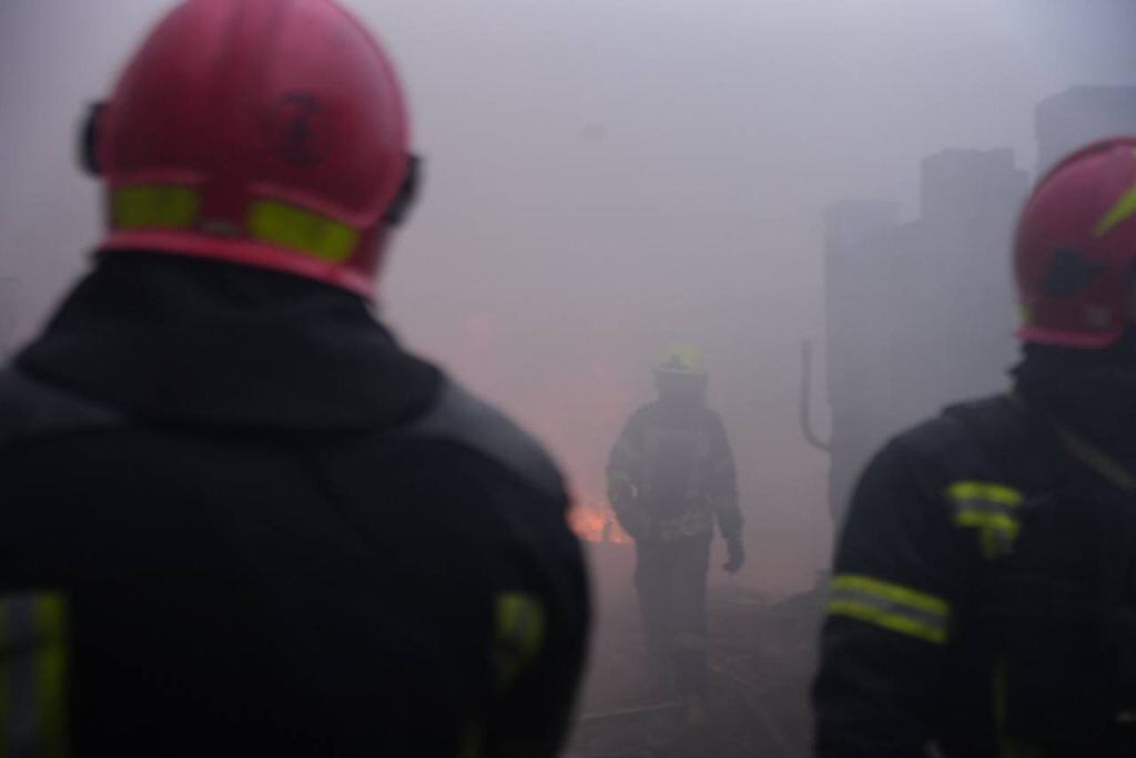 Los bomberos ucranianos extinguen el fuego en el lugar mientras los civiles esperan después de los ataques rusos dirigidos a diferentes lugares del país, que mataron e hirieron a civiles, destruyeron edificios y automóviles y provocaron incendios en Odessa, Ucrania, el 15 de marzo de 2024.