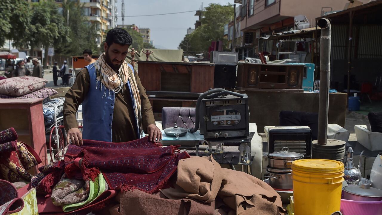 Esta foto tomada el 12 de septiembre de 2021 muestra a un hombre mirando artículos domésticos de segunda mano a la venta en un mercado en el barrio noroeste de Khair Khana en Kabul. - Los mercados de pulgas de Kabul están repletos de pertenencias que afganos desesperados han vendido a precios bajísimos para financiar largos viajes para escapar del país o simplemente para pagar la comida. (Foto de WAKIL KOHSAR / AFP)