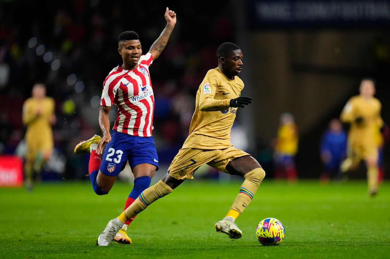 Atletico Madrid's Reinildo Mandava, left, and Barcelona's Ousmane Dembele challenge for the ball during the Spanish La Liga soccer match between Atletico Madrid and FC Barcelona at Civitas Metropolitano stadium in Madrid