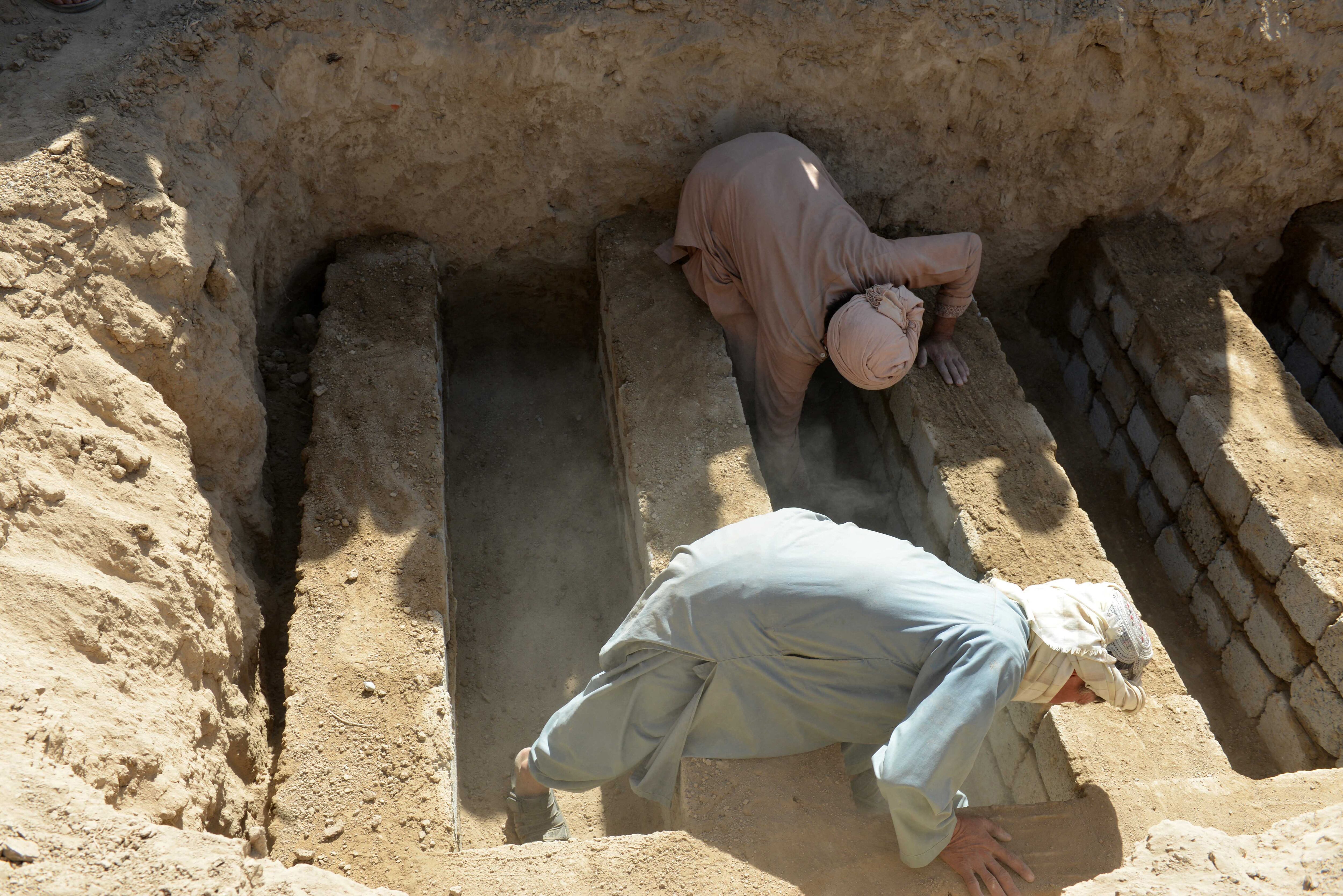 Hombres cubren con tierra la tumba de las víctimas durante el entierro de un cementerio en Kandahar.