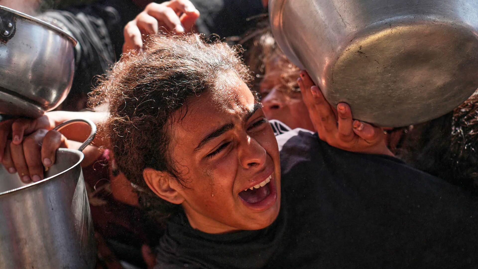 Una niña palestina lucha por obtener comida donada en una cocina comunitaria en Khan Younis, en el sur de la Franja de Gaza, el viernes 9 de mayo de 2025.