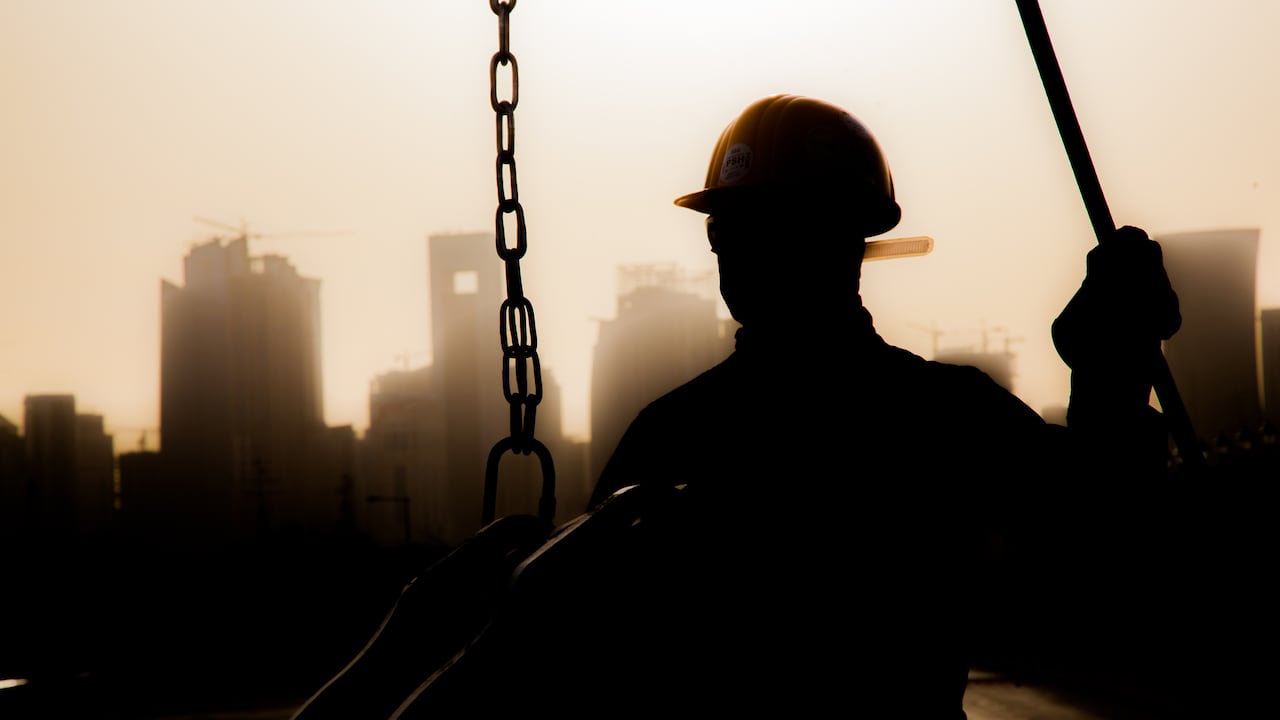 Doha, Qatar - 11 de diciembre de 2017. Trabajadores de la construcción preparando una grúa para trabajar en los rascacielos de fondo en Doha