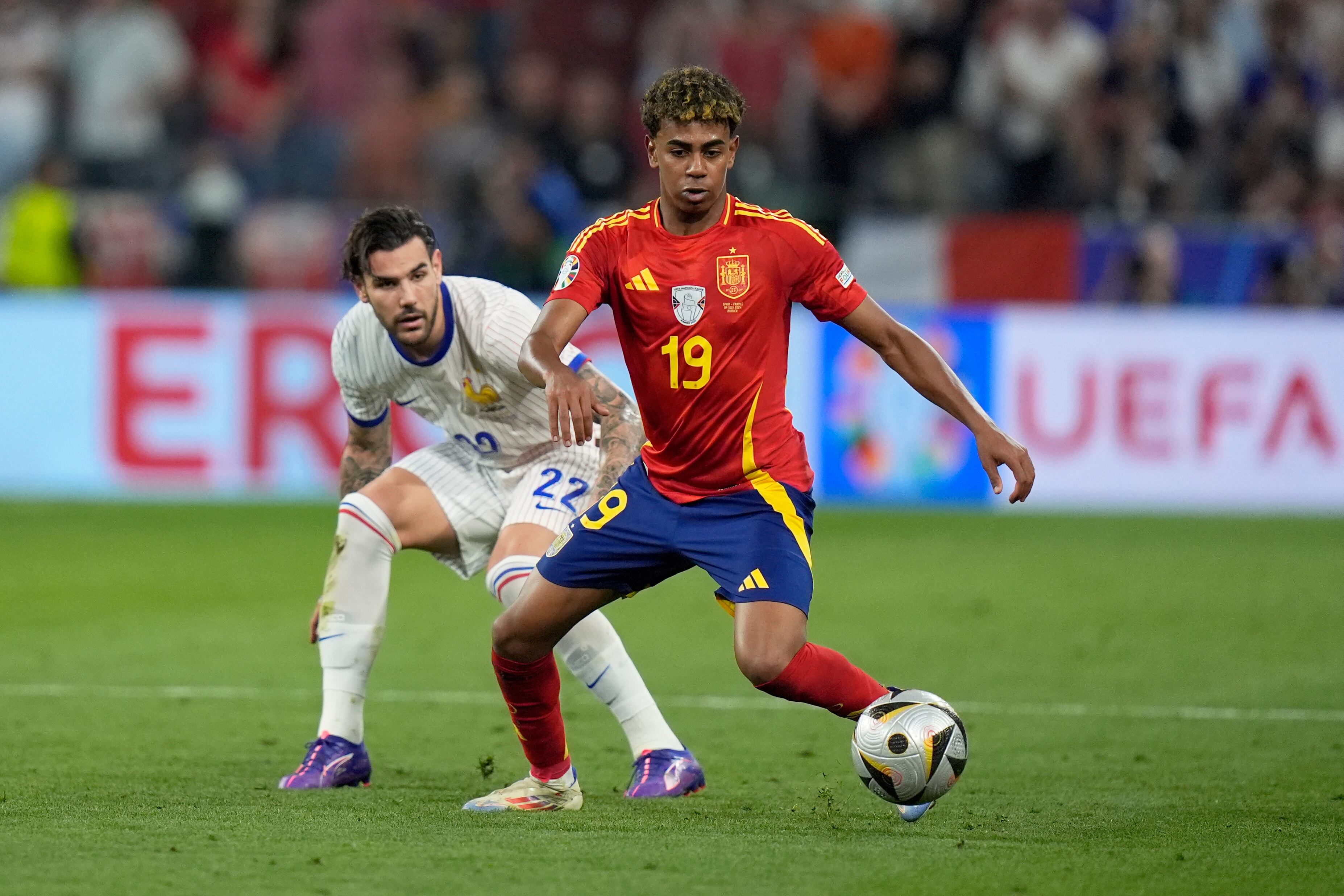 El español Lamine Yamal controla el balón frente a Theo Hernández de Francia, izquierda, durante un partido de semifinal entre España y Francia en el torneo de fútbol Euro 2024 en Munich, Alemania, el martes 9 de julio de 2024. (Foto AP/Matthias Schrader)