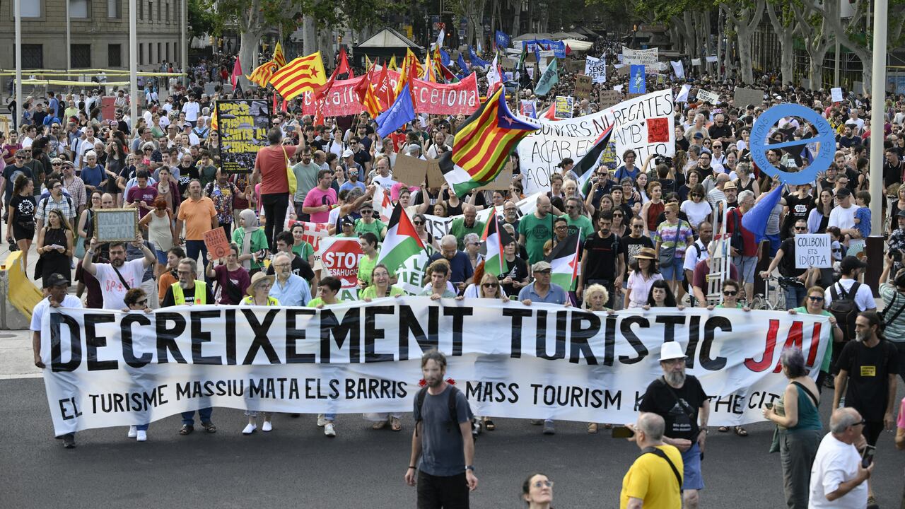 Los manifestantes sostienen carteles que dicen "Disminución del turismo" durante una protesta contra el turismo de masas en el callejón de Las Ramblas de Barcelona, el 6 de julio de 2024.