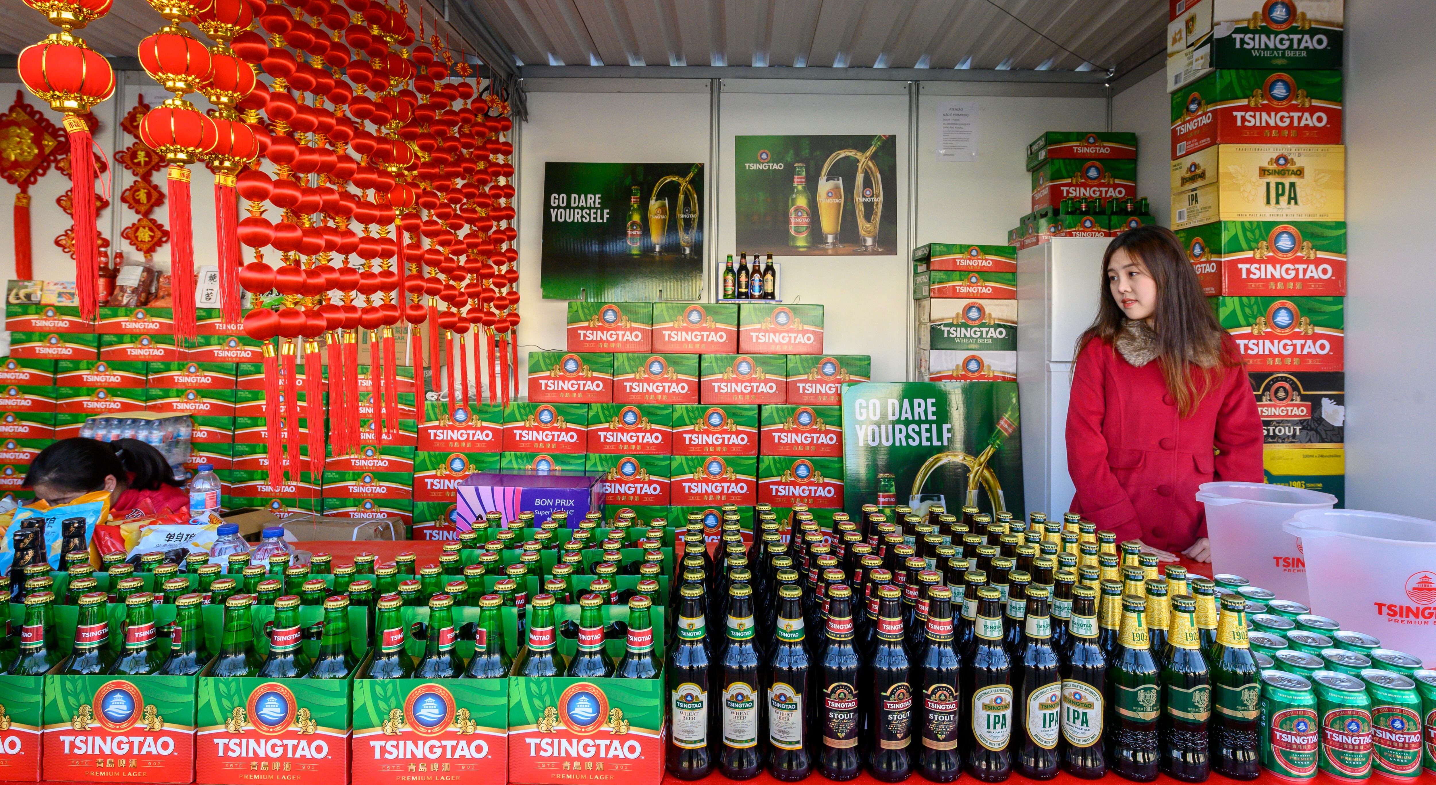Un asistente está rodeado de botellas y latas de cerveza china Tsingtao en exhibición en un stand en el Parque Alameda, donde lugareños y residentes chinos en Portugal se reúnen para celebrar el Año Nuevo