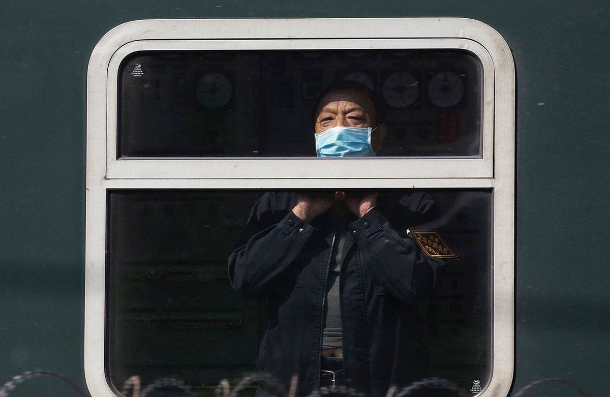 Un hombre con tapabocas se asoma desde un tren cuando llega a Beijing, el martes 28 de abril de 2020. Andy Wong / AP