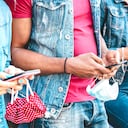 Primer plano de las manos de los amigos con tapabocas, usando la aplicación de seguimiento en teléfonos inteligentes móviles