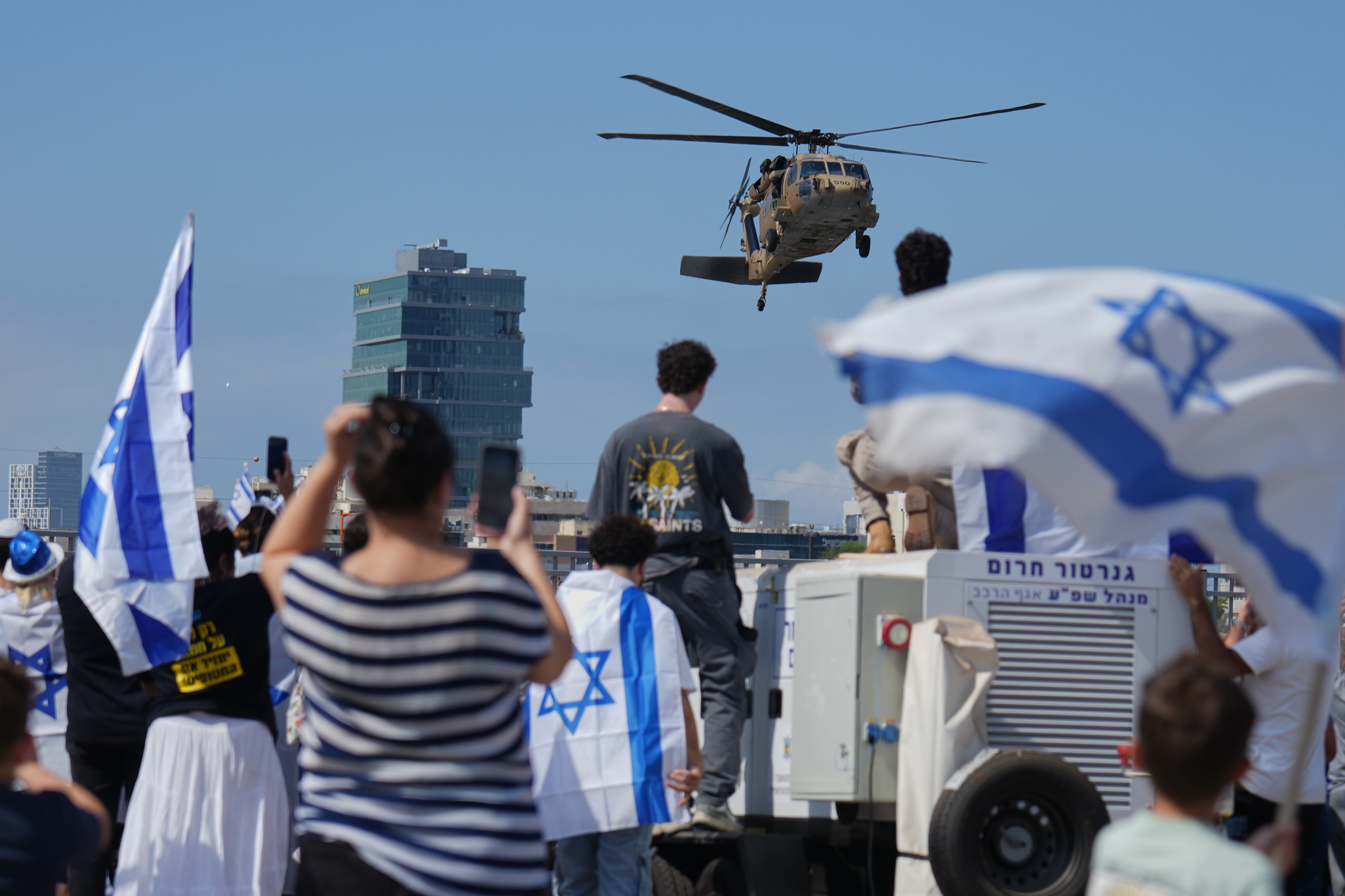 La gente ondea banderas israelíes en señal de celebración mientras esperan afuera del Hospital Beilinson en Petah Tikva, Israel, la llegada de algunos de los secuestrados liberados.