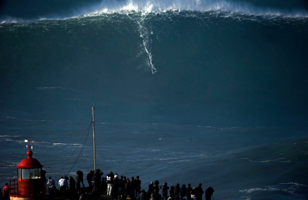 Un surfista se desliza sobre una gran ola durante una sesión de surf en Praia do Norte en Nazare, Portugal. El lugar es famoso mundialmente por el tamaño de sus olas. (AP)