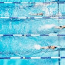Young female competitive swimmers racing in outdoor pool overhead view
