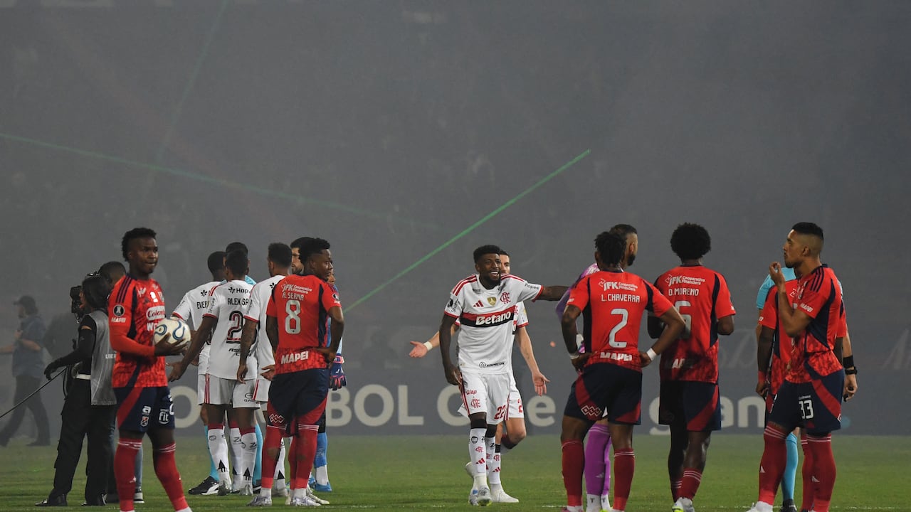 Jugadores de Medellín y Flamengo dialogan entre una nube de humo en el estadio Atanasio Girardot.