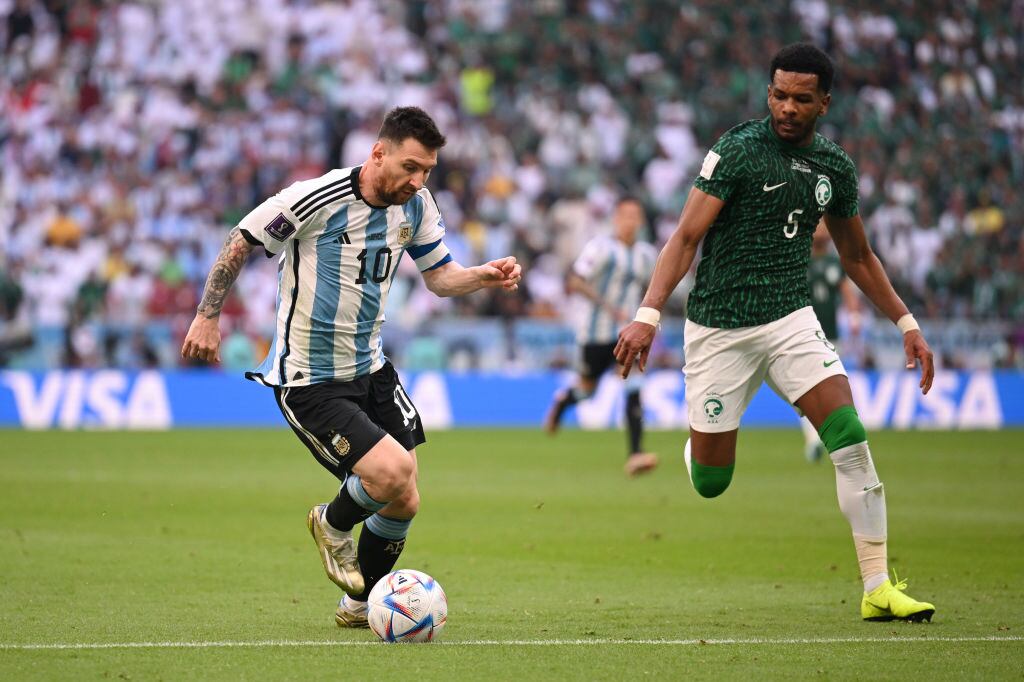 LUSAIL CITY, QATAR - NOVEMBER 22: Lionel Messi of Argentina is challenged by Ali Al-Bulayhi of Saudi Arabia during the FIFA World Cup Qatar 2022 Group C match between Argentina and Saudi Arabia at Lusail Stadium on November 22, 2022 in Lusail City, Qatar. (Photo by Matthias Hangst/Getty Images)