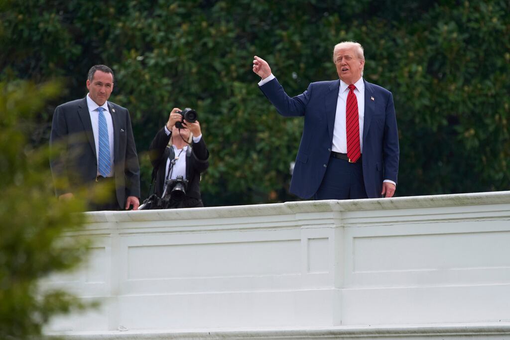 El presidente Donald Trump, en el centro, hace un gesto mientras observa el terreno desde el tejado sobre la columnata que conduce al Ala Oeste de la Casa Blanca, el martes 5 de agosto de 2025, en Washington. (Foto AP/Evan Vucci)