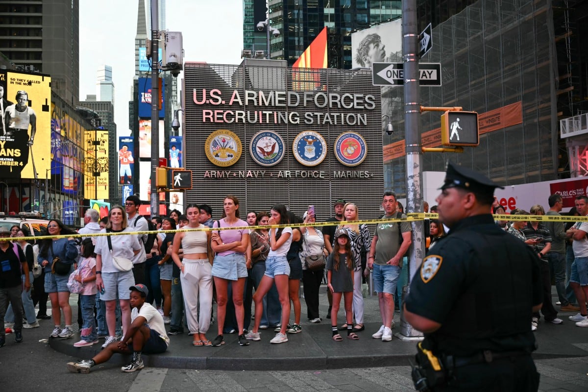 Varias personas observan la escena donde un tiroteo en el que se vio involucrado un agente de policía dejó dos muertos cerca de Times Square.