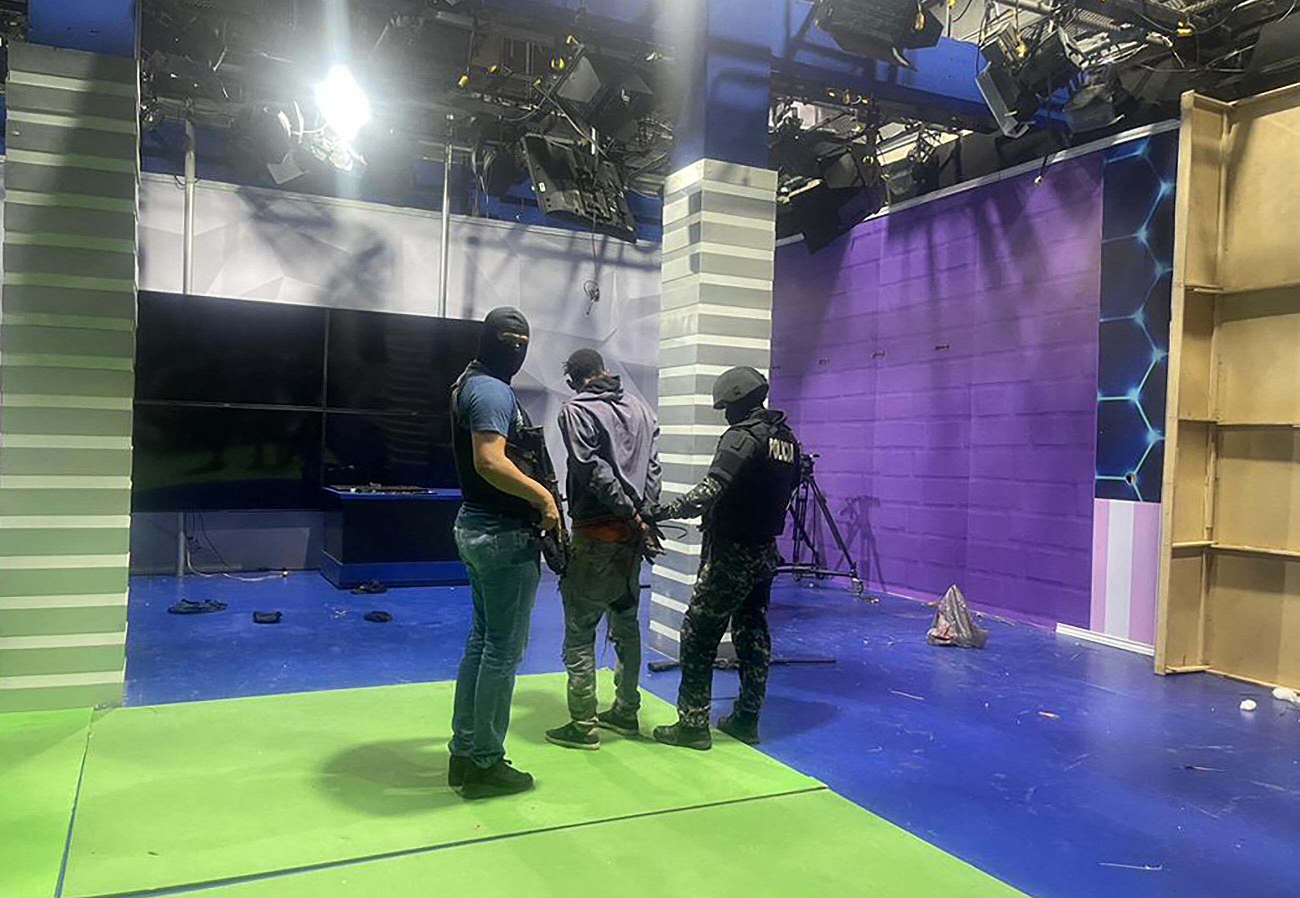 Agentes de policía arrestan a uno de los pistoleros no identificados que irrumpieron en un estudio de la televisión estatal TC en vivo, en Guayaquil, Ecuador, el 9 de enero de 2024, un día después de que el presidente ecuatoriano Daniel Noboa declarara el estado de emergencia tras la fuga de prisión de un peligroso jefe narco. Se escucharon disparos en la televisión en vivo en un Ecuador devastado por la violencia cuando hombres armados con rifles y granadas irrumpieron en el estudio poco después de que gánsteres prometieran una "guerra" contra los planes del presidente de recuperar el control de manos de los "narcoterroristas". (Foto de AFP)