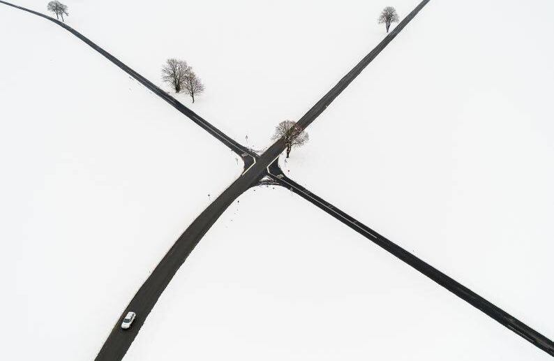 4 de abril - Vista aérea de un automóvil que se abre paso junto a un campo de paisaje recién cubierto de nieve cerca de Sottens, al oeste de Suiza. FOTO:  Fabrice COFFRINI / AFP