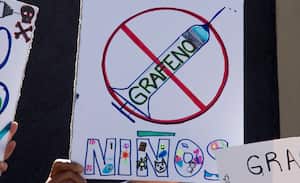 Una mujer sostiene un cartel durante una manifestación contra la vacunación obligatoria COVID-19 para niños en San José, el 5 de enero de 2022. (Photo by Ezequiel BECERRA / AFP)