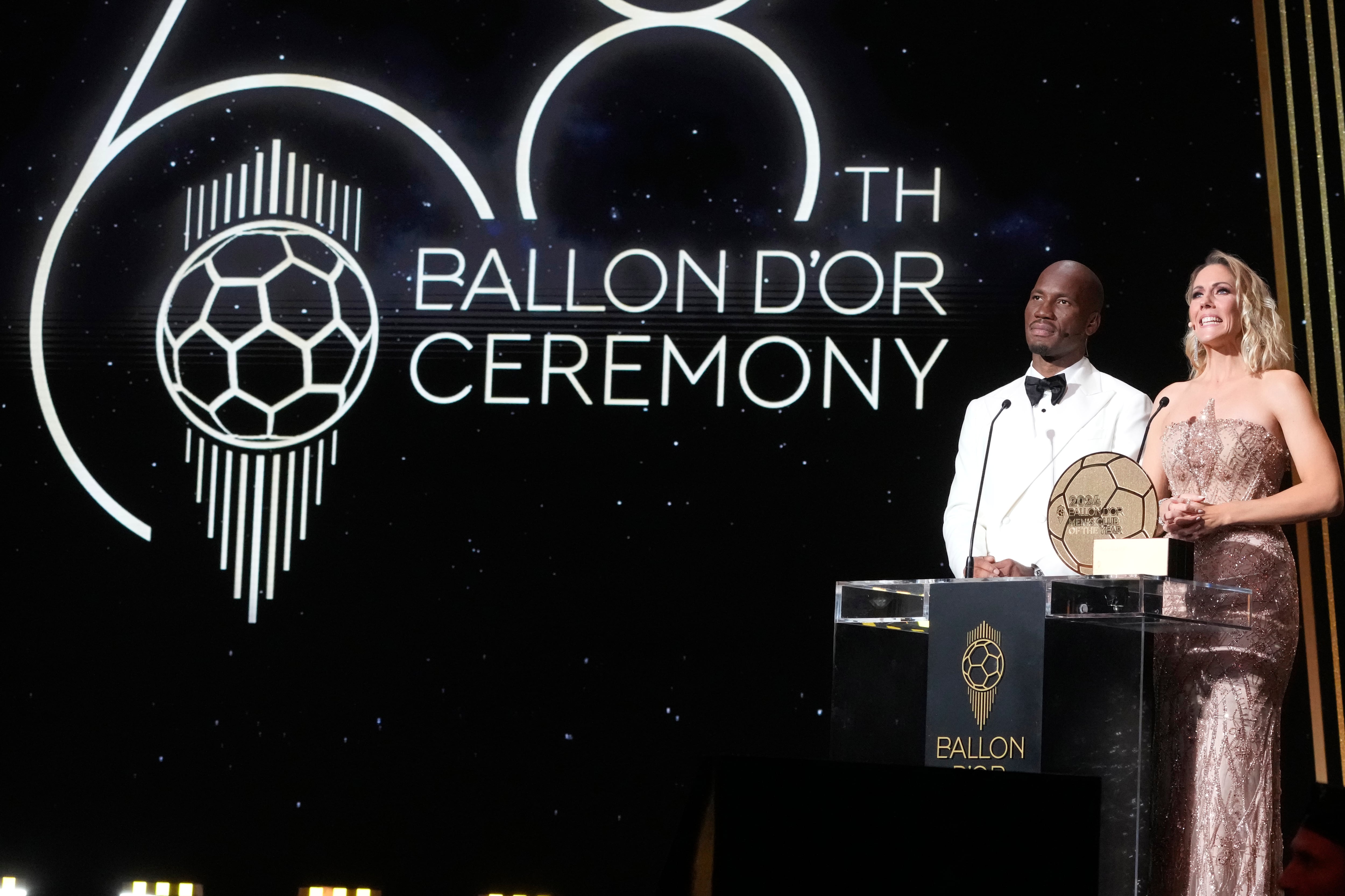 Ivorian former football player Didier Drogba, left, and journalist Sandy Heribert present the 68th Ballon d'Or (Golden Ball) award ceremony at Theatre du Chatelet in Paris, Monday, Oct. 28, 2024. (AP Photo/Michel Euler)