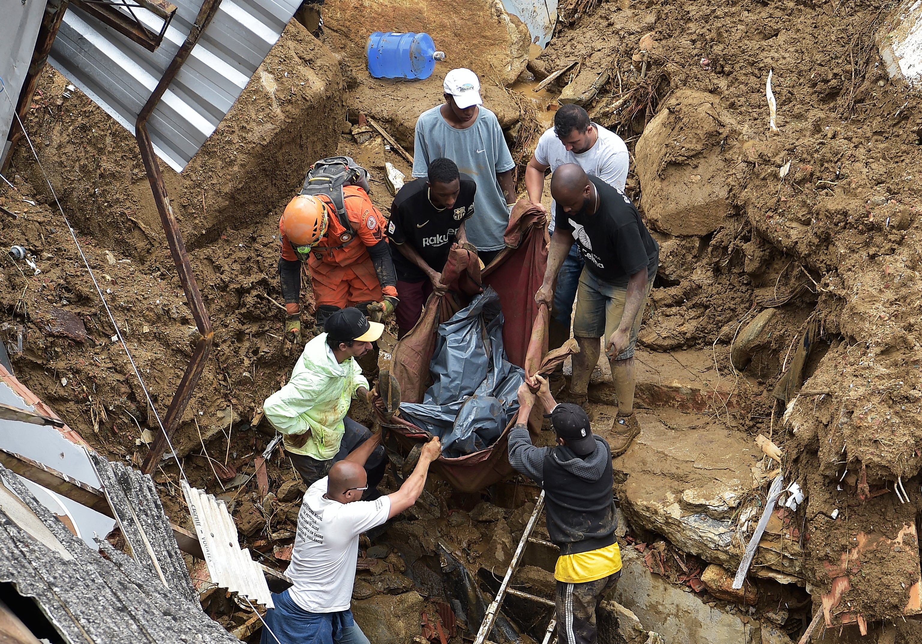 Las personas sacan el cadáver de una víctima de los escombros después de un deslizamiento de tierra en Petrópolis, Brasil, el 16 de febrero de 2022. - Las inundaciones a gran escala destruyeron cientos de propiedades y se cobraron al menos 34 vidas en el área.