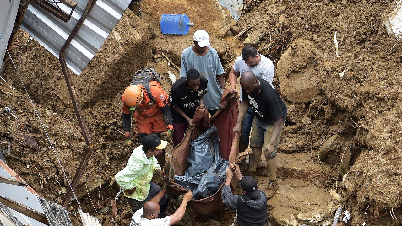Las personas sacan el cadáver de una víctima de los escombros después de un deslizamiento de tierra en Petrópolis, Brasil, el 16 de febrero de 2022. - Las inundaciones a gran escala destruyeron cientos de propiedades y se cobraron al menos 34 vidas en el área.