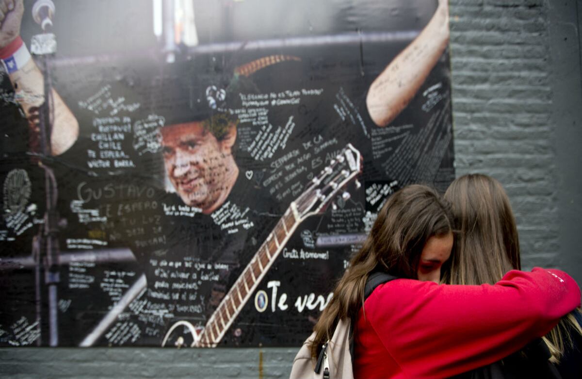 Fanáticos de Gustavo Cerati se abrazan frente a un poster de él colgado frente a la clínica donde estuvo hospitalizado hasta que falleció este jueves. (AP)V