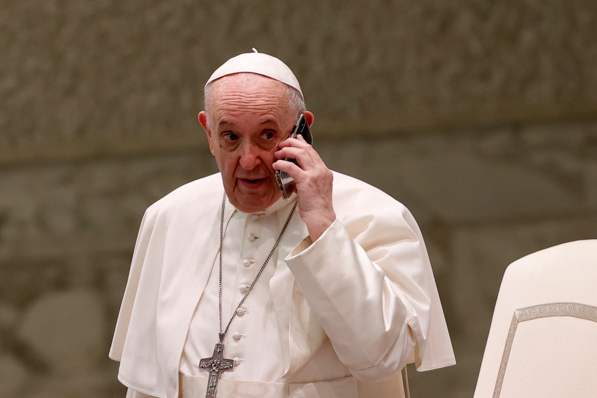 El Papa Francisco habla por un teléfono celular, que le dio su asistente Piergiorgio Zanetti, al final de su audiencia general semanal en la sala Pablo VI del Vaticano, el miércoles 11 de agosto de 2021 (AP Photo / Riccardo De Luca).