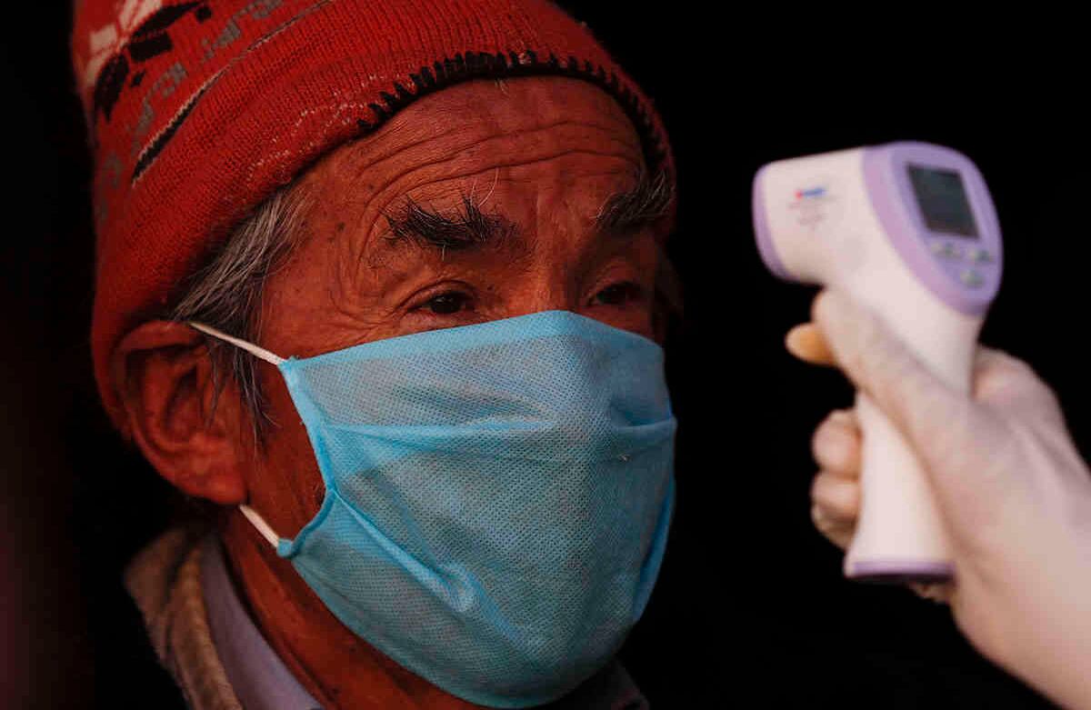 Un residente se queda quieto mientras un trabajador de la salud vestido con un equipo de protección completo mide su temperatura durante una nueva prueba de detección de coronavirus en el barrio Villa Dolores de El Alto, Bolivia, el sábado 18 de julio de 2020. (Foto AP / Juan Karita)