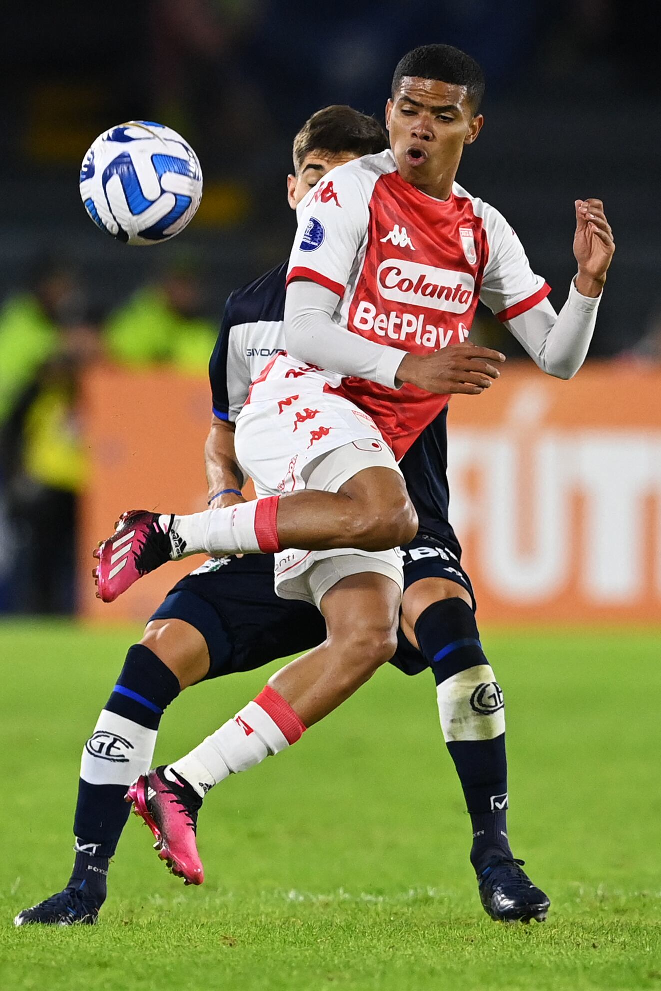 Santa Fe's forward David Enamorado (Front) and Gimnasia y Esgrima's midfielder Matias Miranda (Back) vie for the ball during the Copa Sudamericana group stage football match between Independiente Santa Fe and Gimnasia y Esgrima at El Campin stadium in Bogota on April 18, 2023. (Photo by Juan BARRETO / AFP)