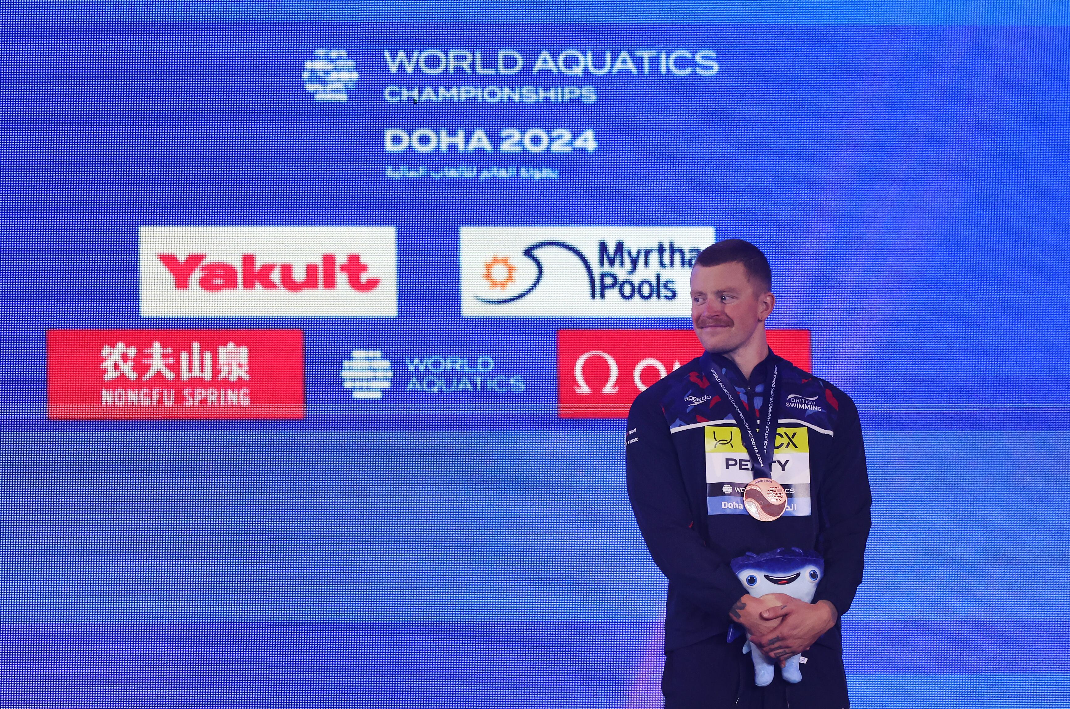 Adam Peaty, del equipo de Gran Bretaña, celebra en el podio su medalla de bronce en los 100 metros braza masculinos durante la undécima jornada de los Campeonatos Mundiales Acuáticos de Doha 2024 en el Aspire Dome el 12 de febrero de 2024 en Doha, Qatar.