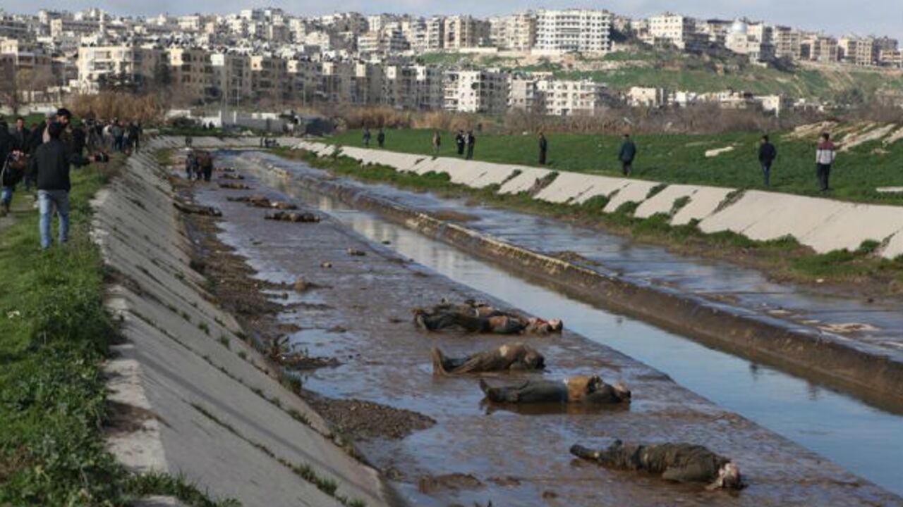 Sirios observan los cadáveres que aparecieron en un pequeño canal situado en un barrio de Alepo bajo control del Gobierno, en Siri