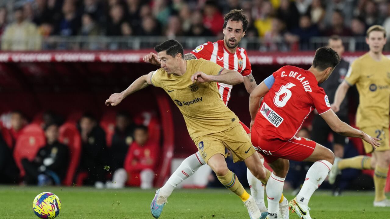 Barcelona's Robert Lewandowski, left, tussles for the ball with Almeria's Cesar de la Hoz during the Spanish La Liga soccer match between Almeria and Barcelona at the Juegos Mediterraneos stadium in Almeria, Spain, Sunday, Feb. 26, 2023. (AP/Jose Breton)